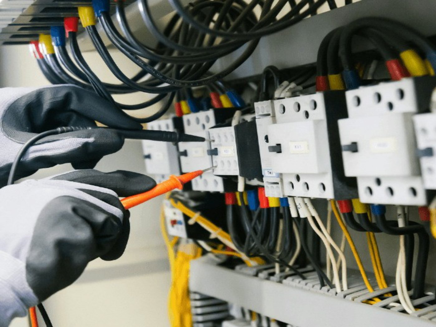 Gloved hands wiring an electrical control panel