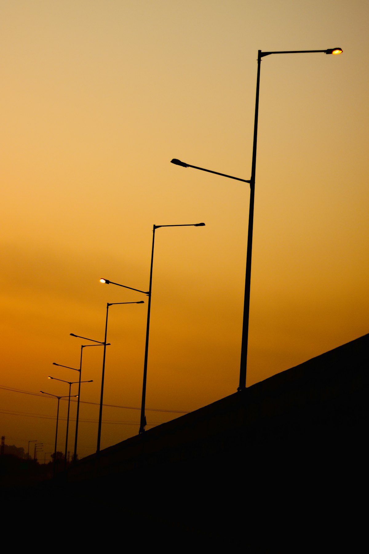 Streetlight poles against an amber evening sky